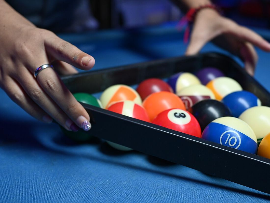 Mâini care așază triunghiul cu bile pe o masă de pool